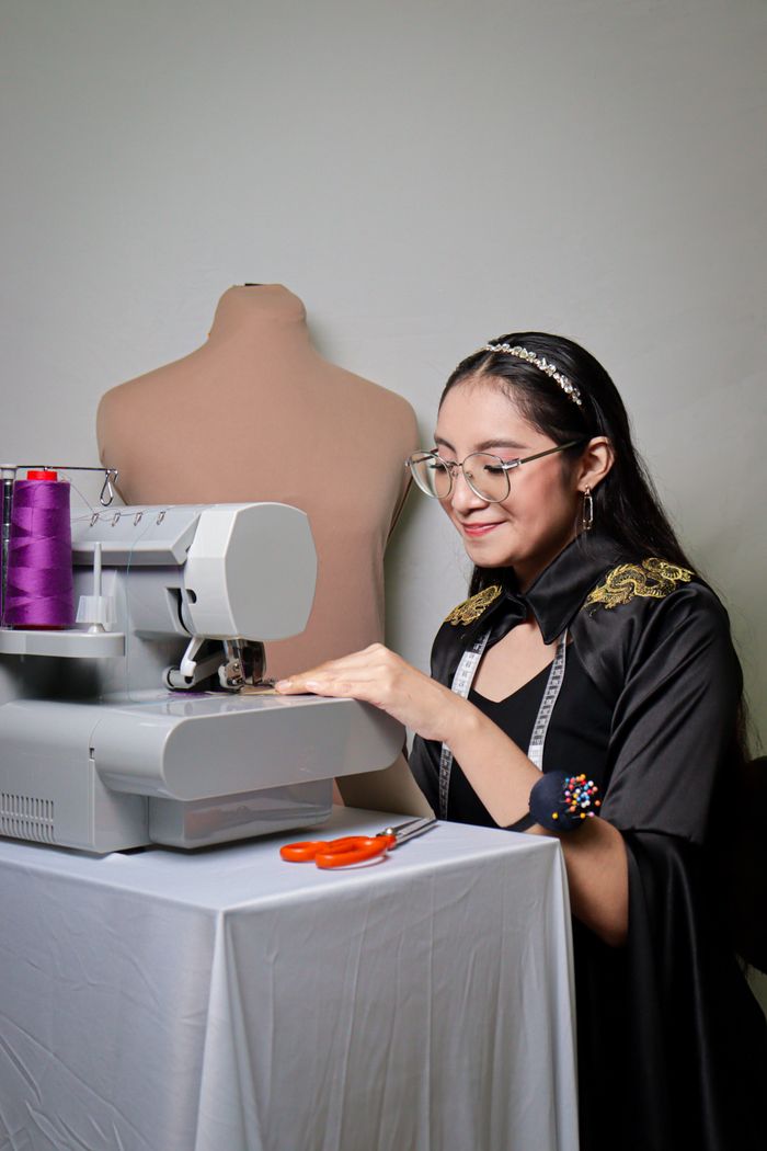 A focused female seamstress operates a sewing machine indoors, showcasing craftsmanship.